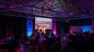 Foto van het Kennispoort Regio Zwolle Café. Publiek in de zaal kijkend naar het podium met twee sprekers