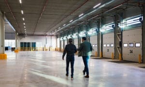 Foto van de rug van twee personen lopend in een loods